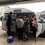 Eine Filmcrew, die von aussen durch die offene Vantüre filmen.